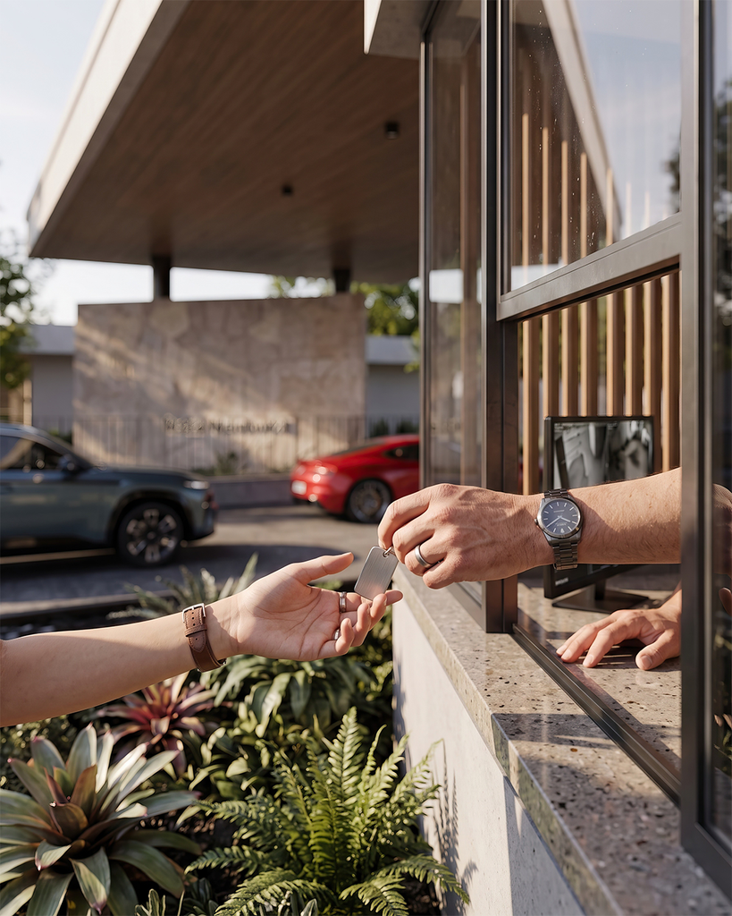 Detalle de manos junto a la vegetación del acceso, auto en segundo plano